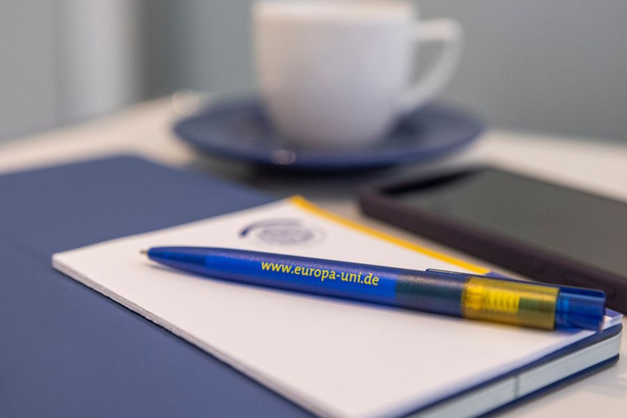 Notizblock mit Stift, Tasse und Handy im Hintergrund