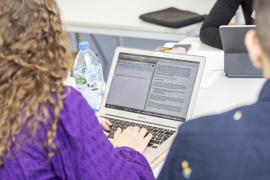 Zwei Studierende sitzen vor einem Laptop