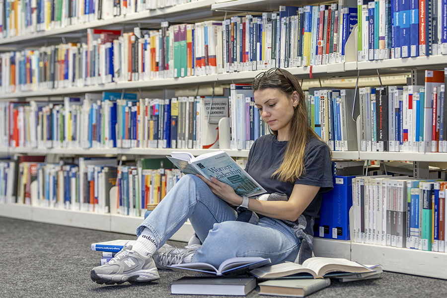 Die Studentin liest Bücher in der Bibliothek